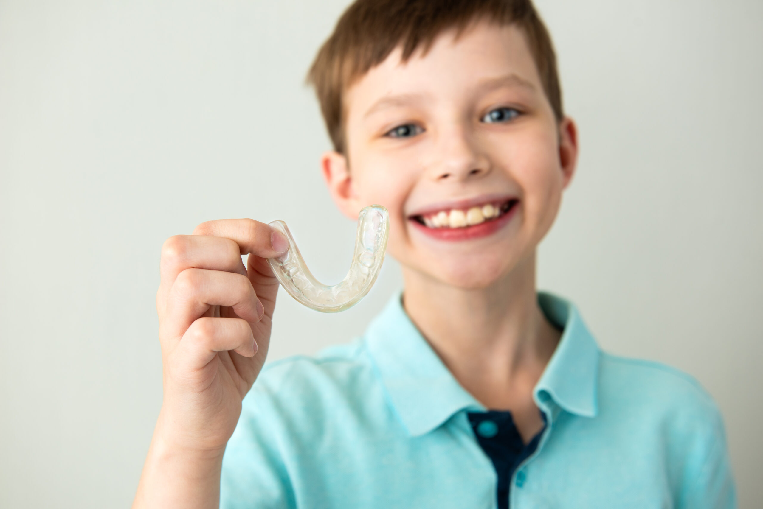 Kid with overbite holding Invisalign retainers.