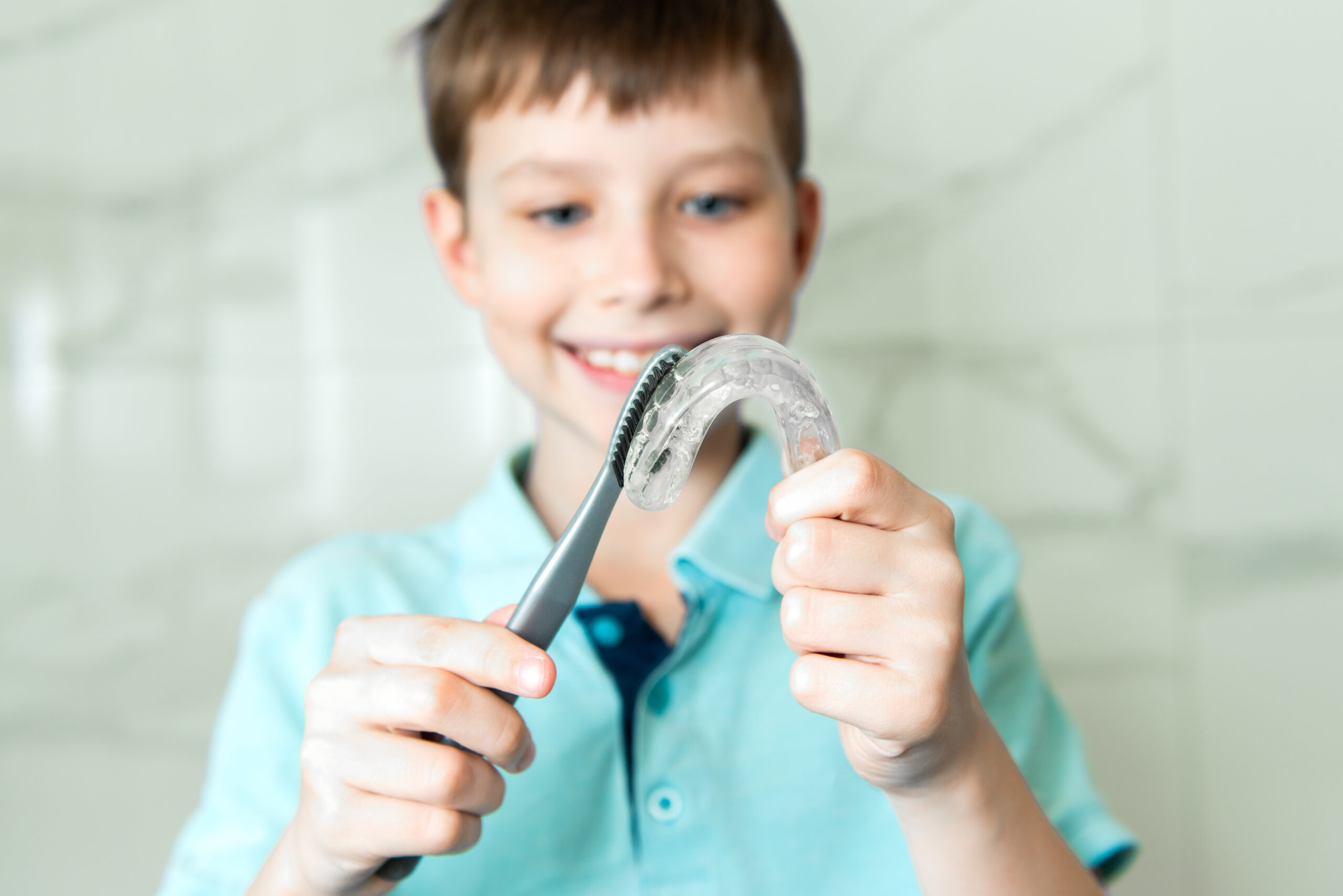 Boy brushing his Invisalign retainer.