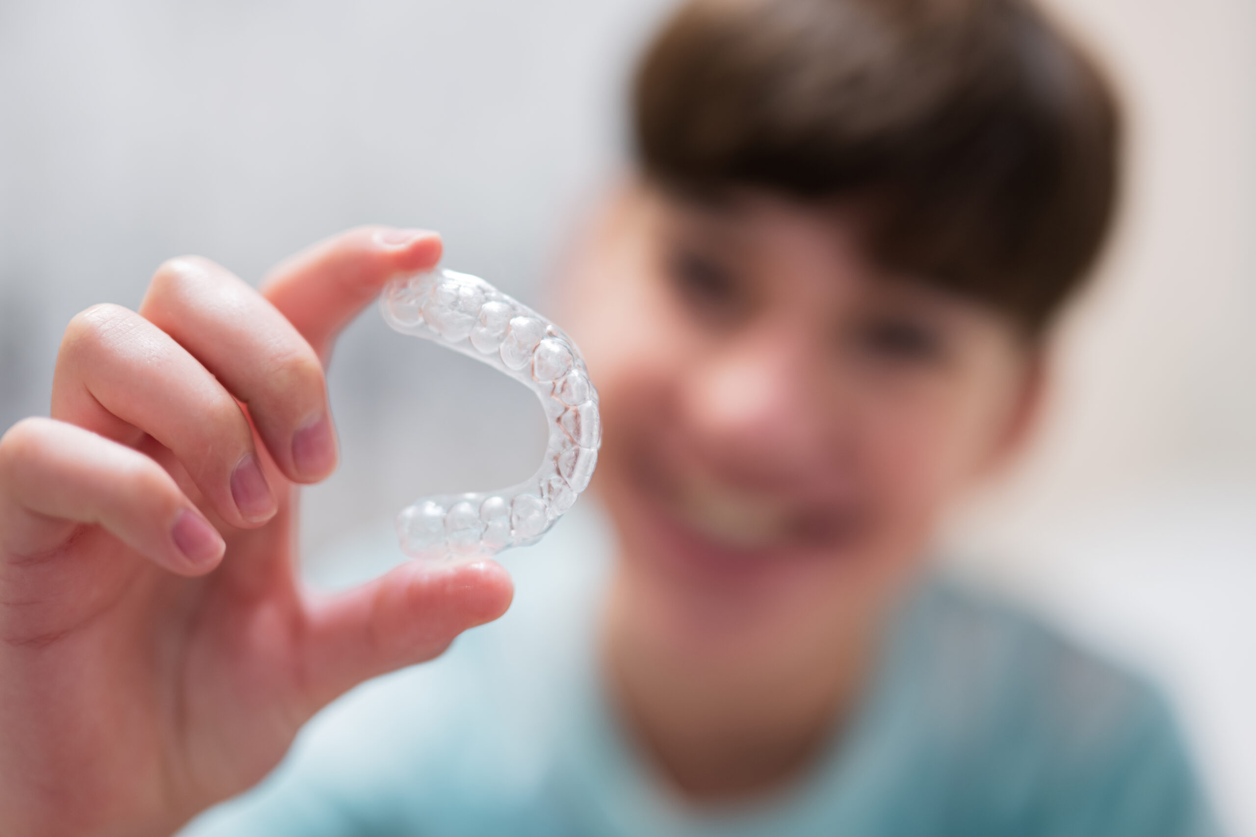 Image of a boy holding invisalign aligners.
