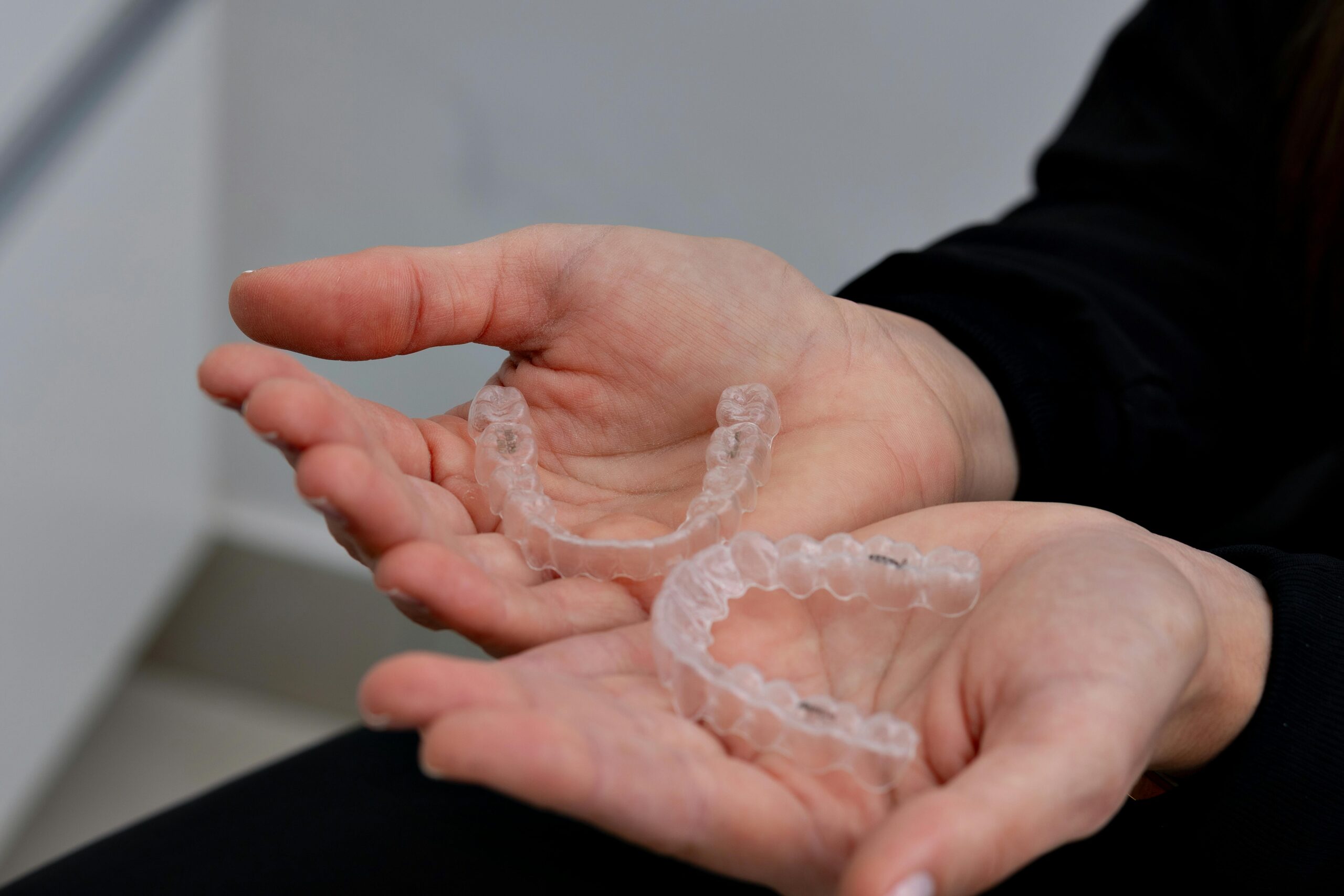 Person holding Invisalign retainers.